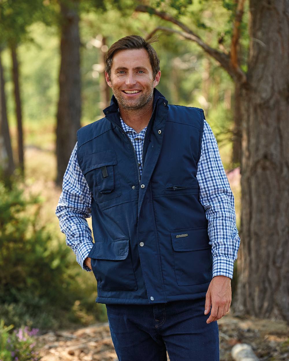 Navy coloured Champion Peak Multi-Pocket Padded Bodywarmer on forest background 
