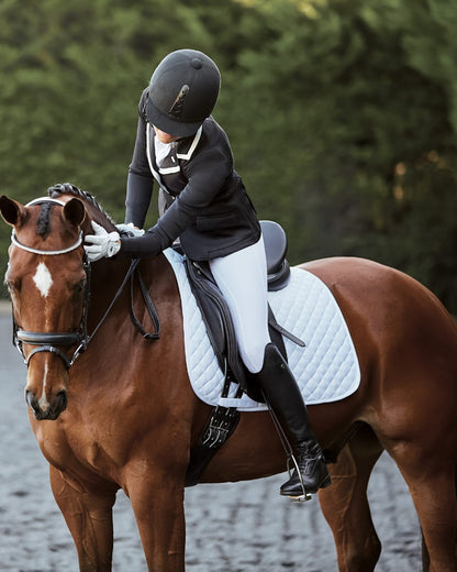 Black coloured Collegiate Lectern Dressage Saddle on blurry green background 