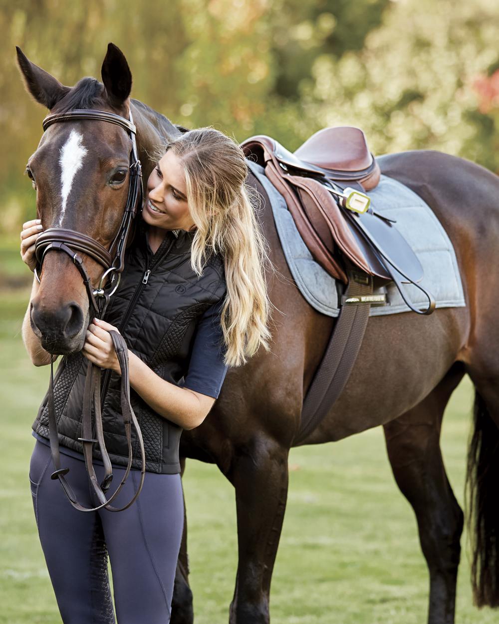 Brown coloured Collegiate Scholar All Purpose Saddle With Round Cantle on blurry green background 