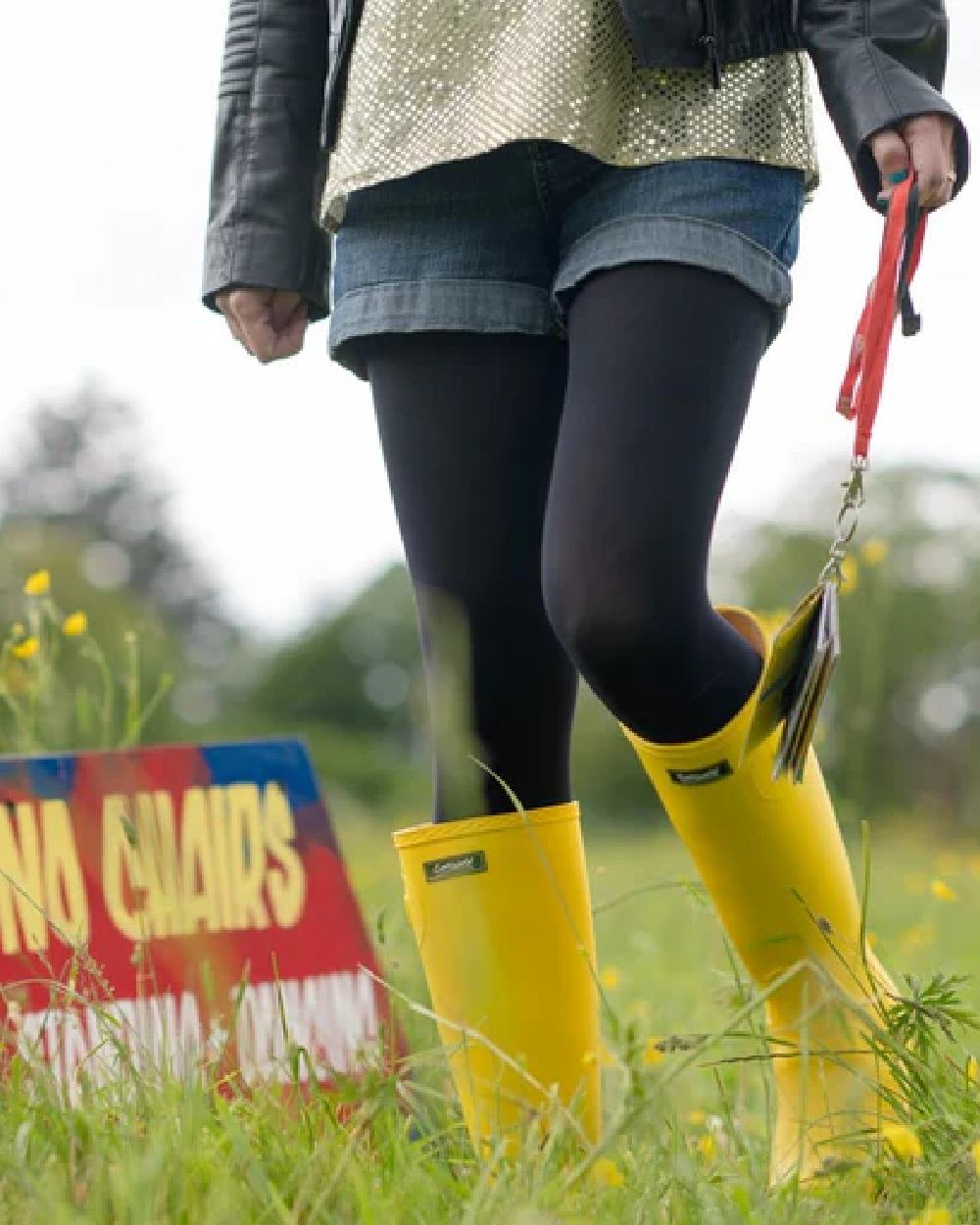 Yellow coloured Cotswold Sandringham Buckle Strap Wellingtons on grassy background 