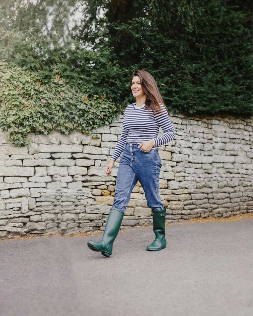 Green coloured Cotswold Windsor Buckle Strap Rubber Wellingtons on street background 