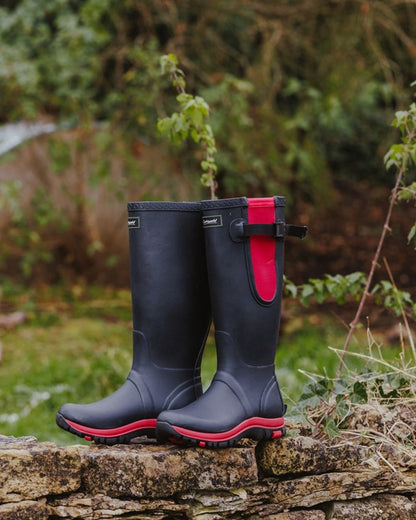 Navy Pink coloured Cotswold Womens Milton Adjustable Wellingtons on forest background 