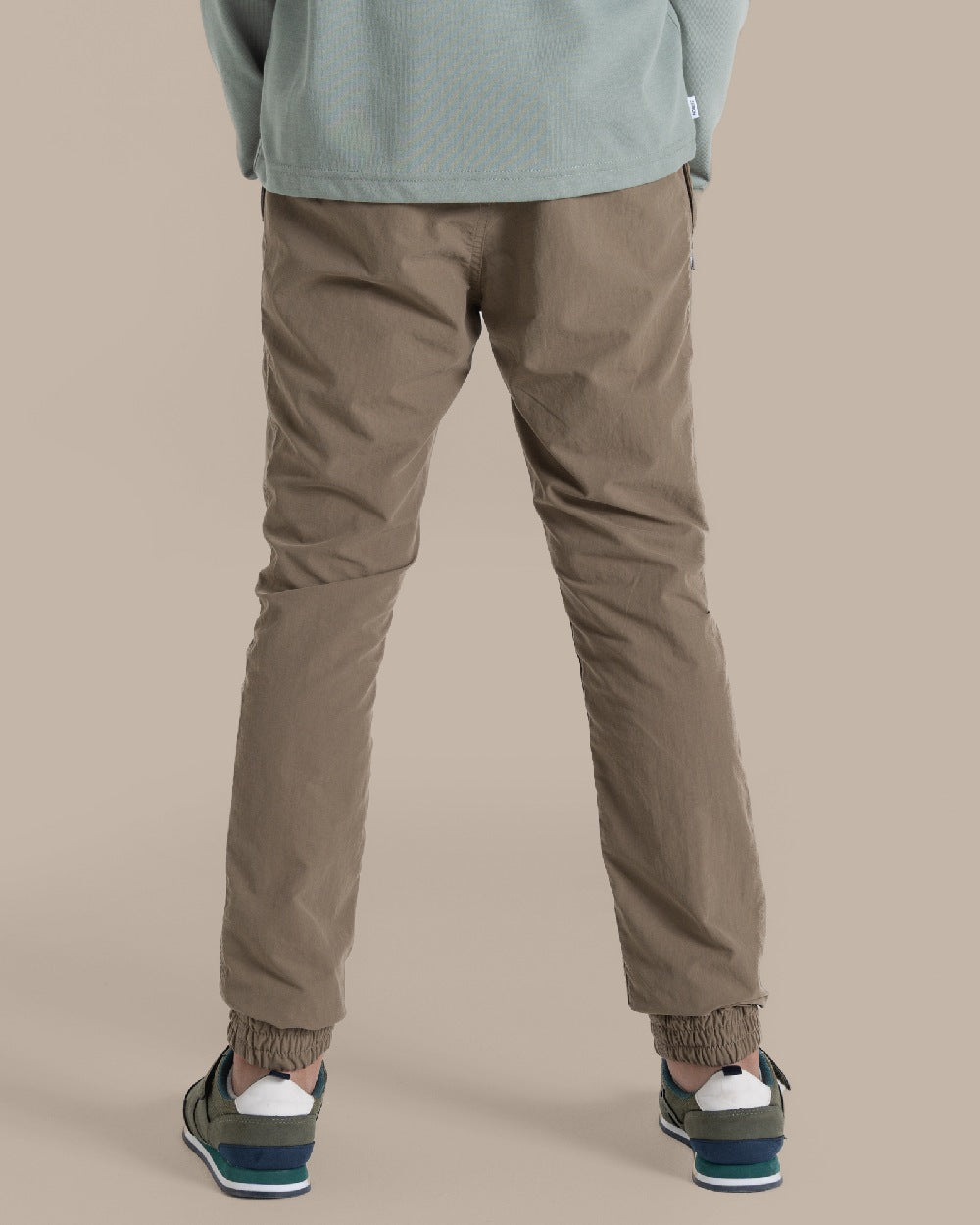 Pebble Coloured Craghoppers Kids Nosilife Pinzon Trousers on Beige Background 