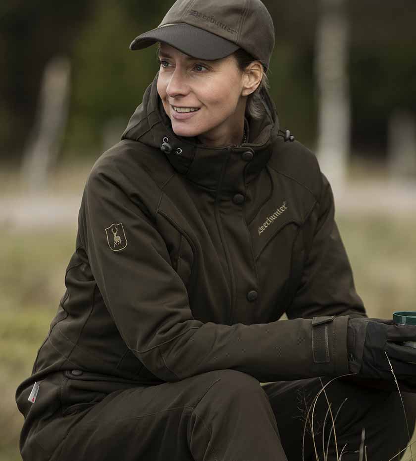 Seated woman wears dark green Lady Gabby shooting jacket | Deerhunter women's Clothing.