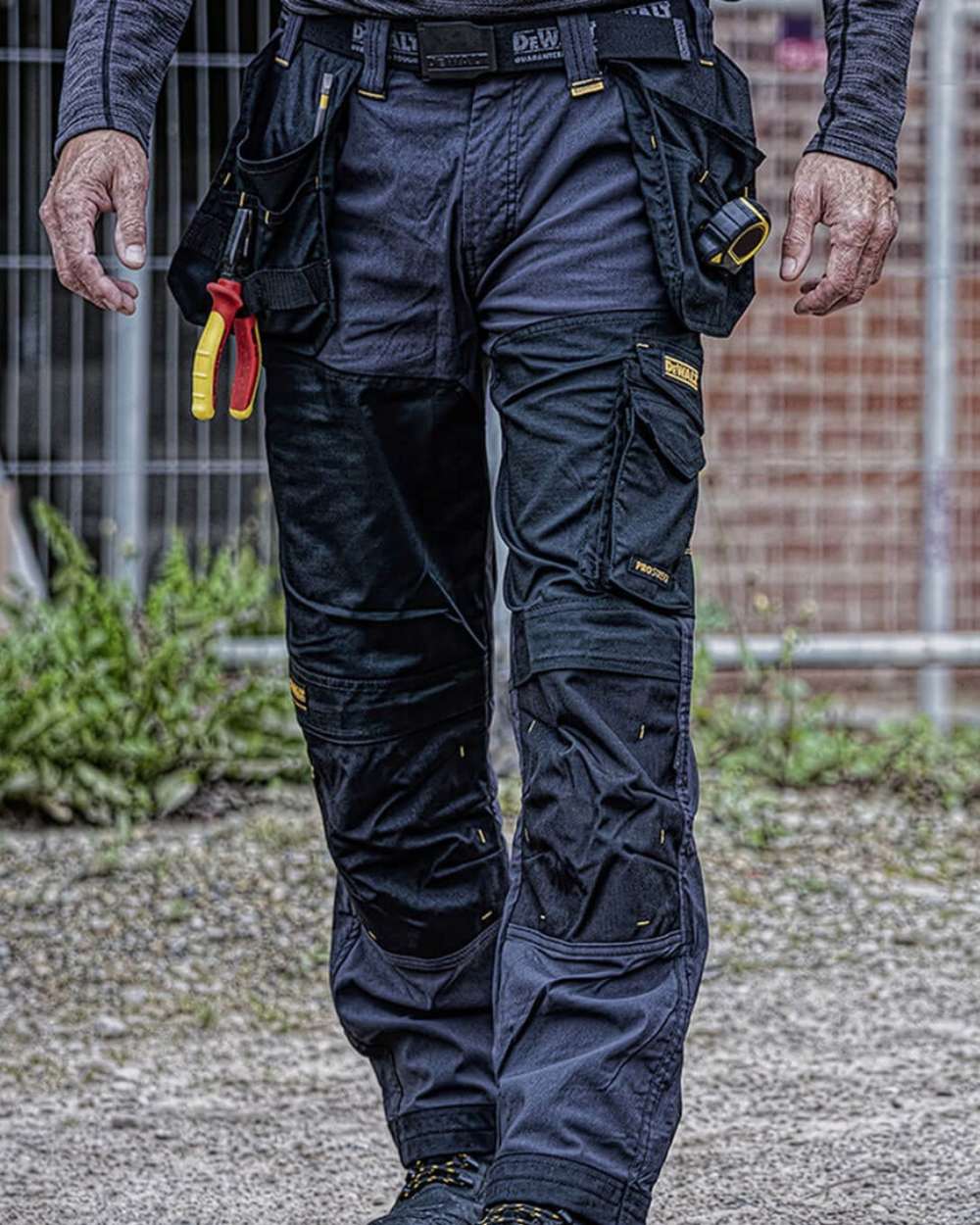 Grey coloured DeWalt Memphis Regular Fit Stretch Trousers on outdoor background 