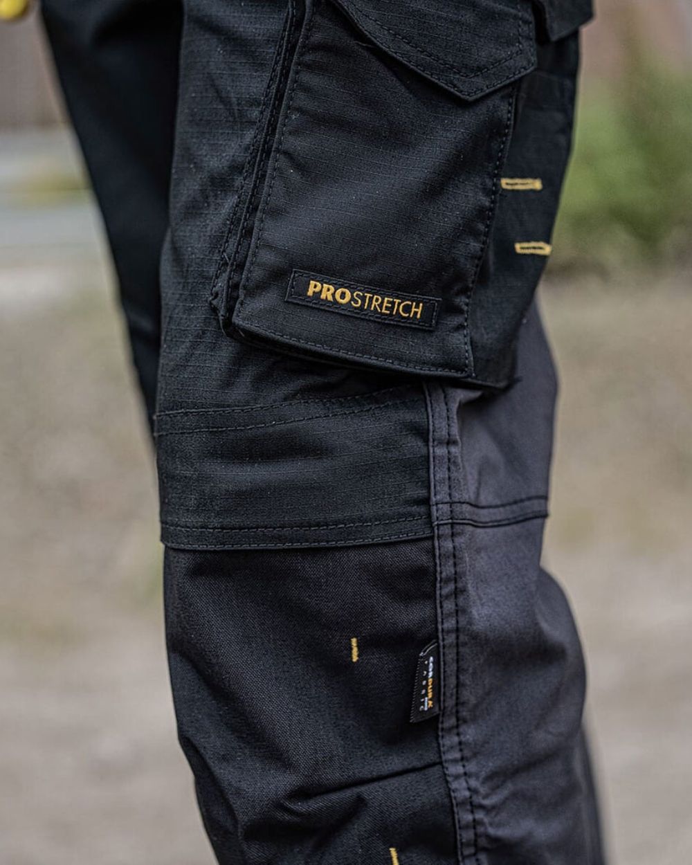 Grey coloured DeWalt Memphis Regular Fit Stretch Trousers on blurry background 