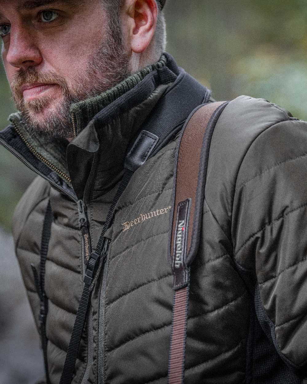 Adventure Green coloured Deerhunter Moor Padded Softshell Jacket on blurry background 