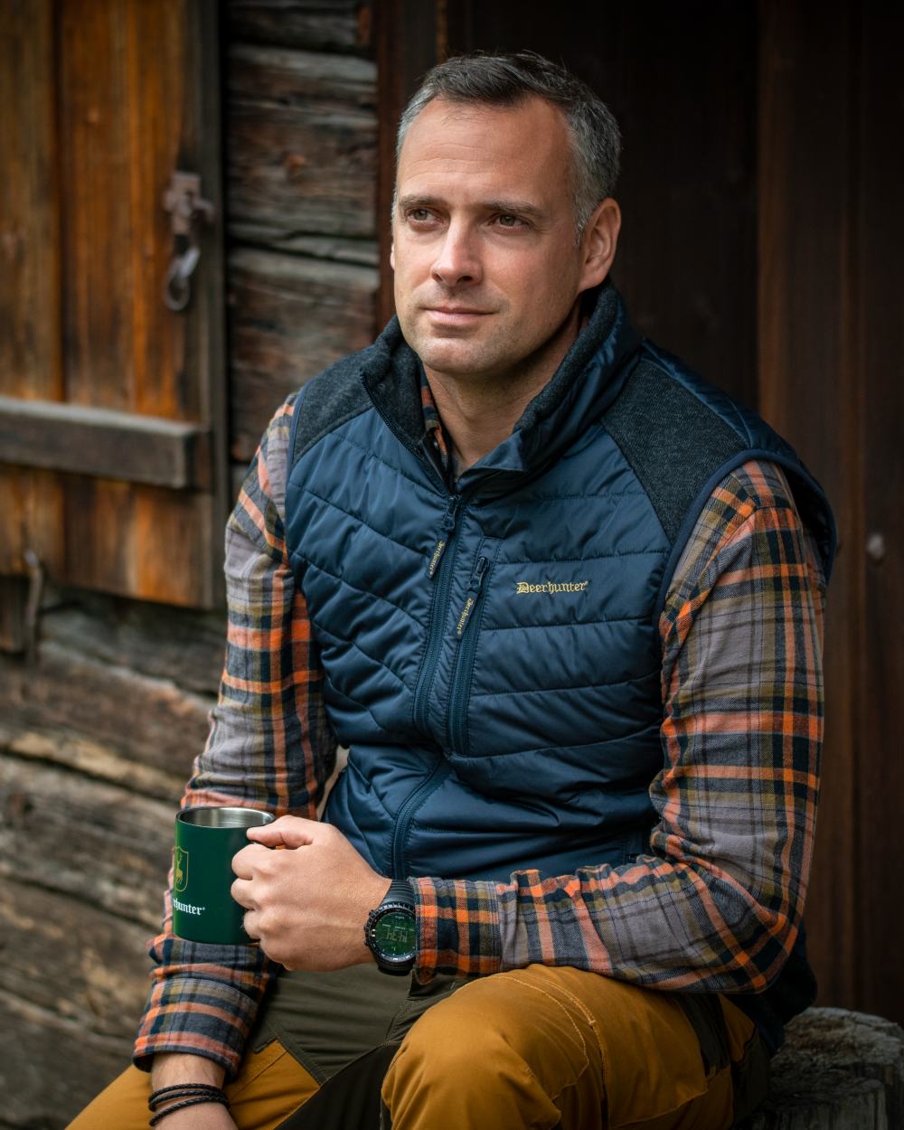 Dark Blue Coloured Deerhunter Moor Padded Waistcoat with Knit on house background 