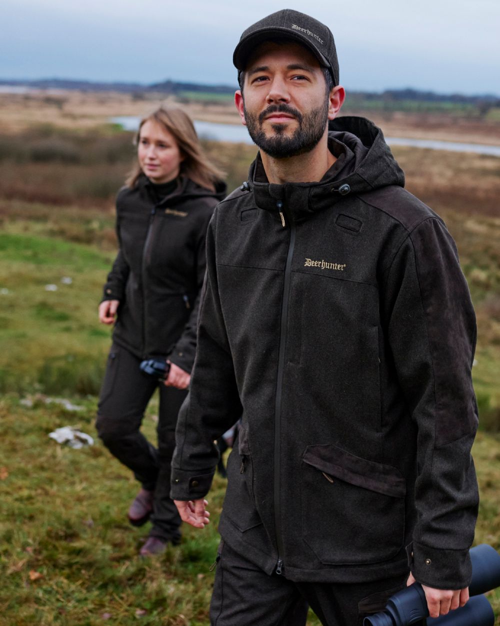 Loden Wood Coloured Deerhunter Tatra Jacket On A Forest Background 