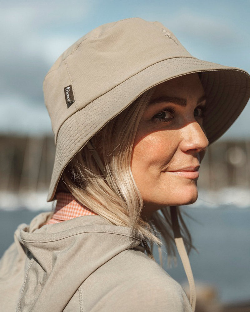 Woman wearing a beige Pinewood bucket hat with a blurred natural background