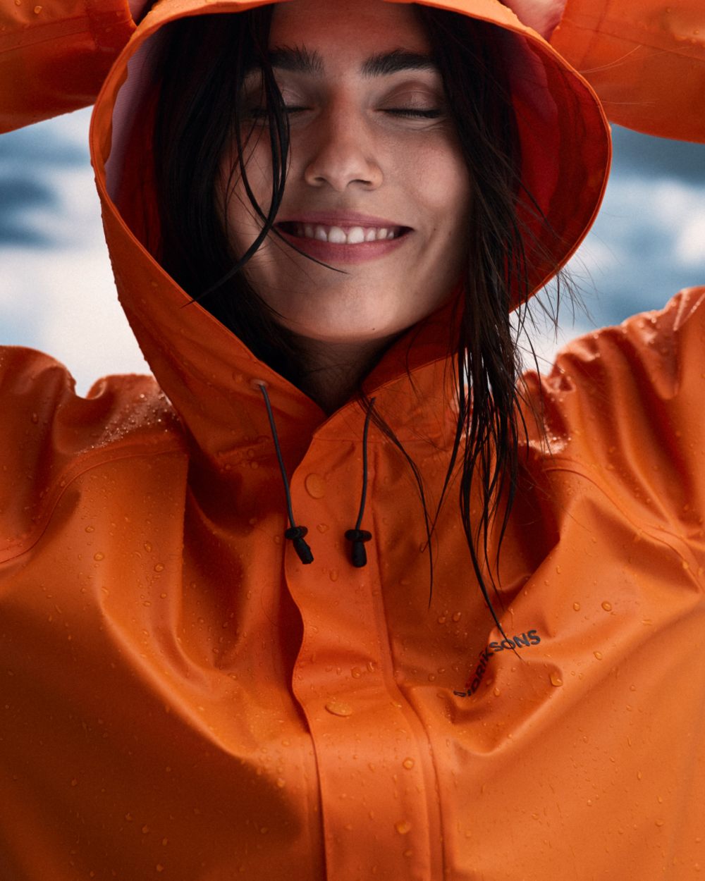Flame coloured Didriksons Avon Parka on sky background 