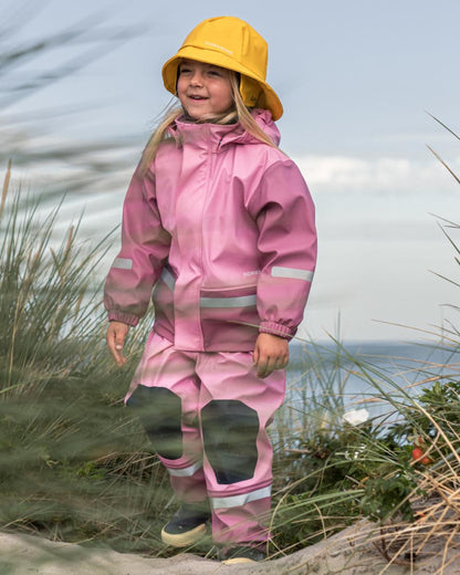 Light Heather Pink coloured Didriksons Boardman Kids Rain Set on sea background 