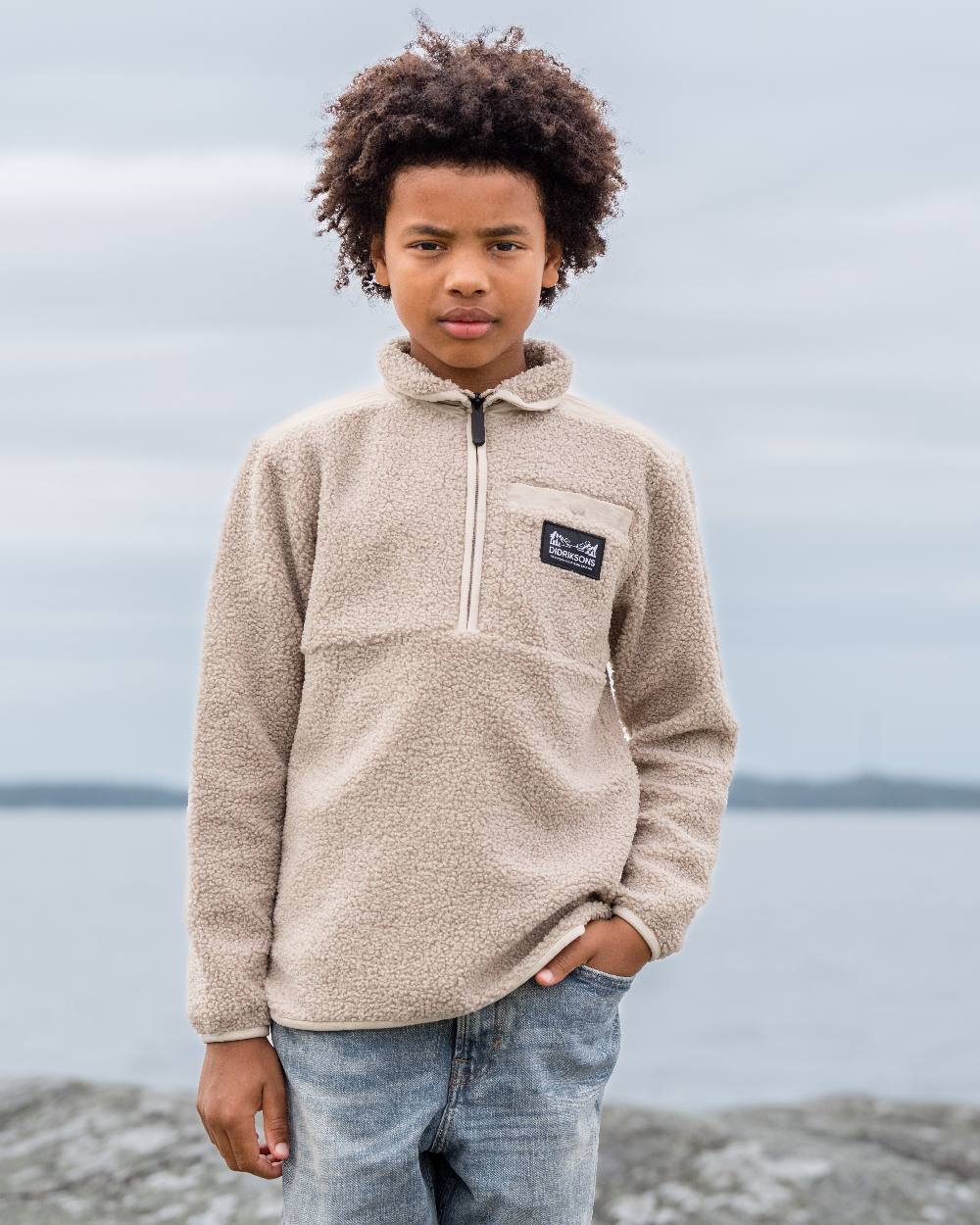 Beach Beige coloured Didriksons Childrens Exa Half Zip Sweater on sea background 
