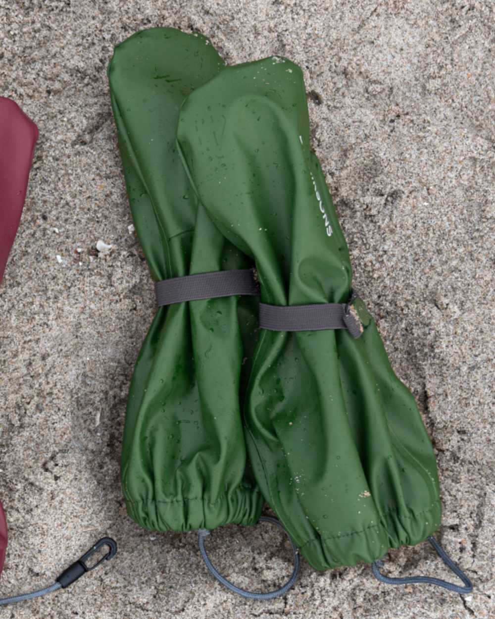 Pine Green coloured Didriksons Childrens Gloves on sand background 