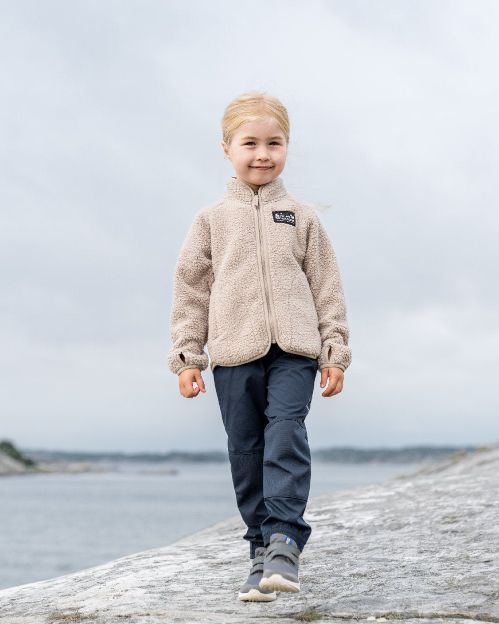 Beach Beige coloured Didriksons Childrens Gibbs Full Zip Jacket 2 on coastal background 