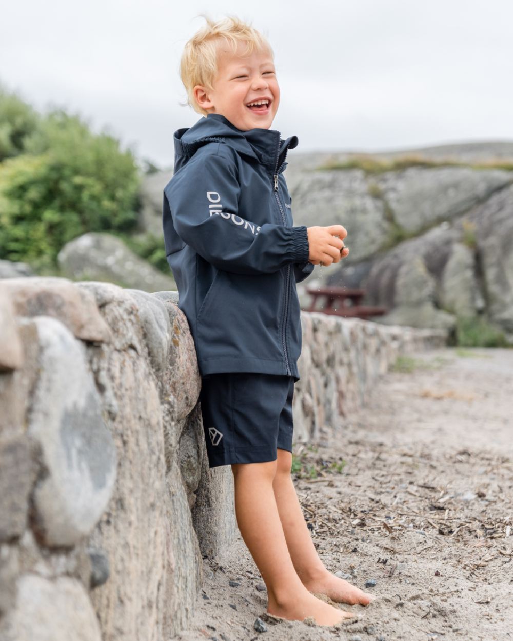 Navy coloured Didriksons Childrens Hallon Jacket on beach background 