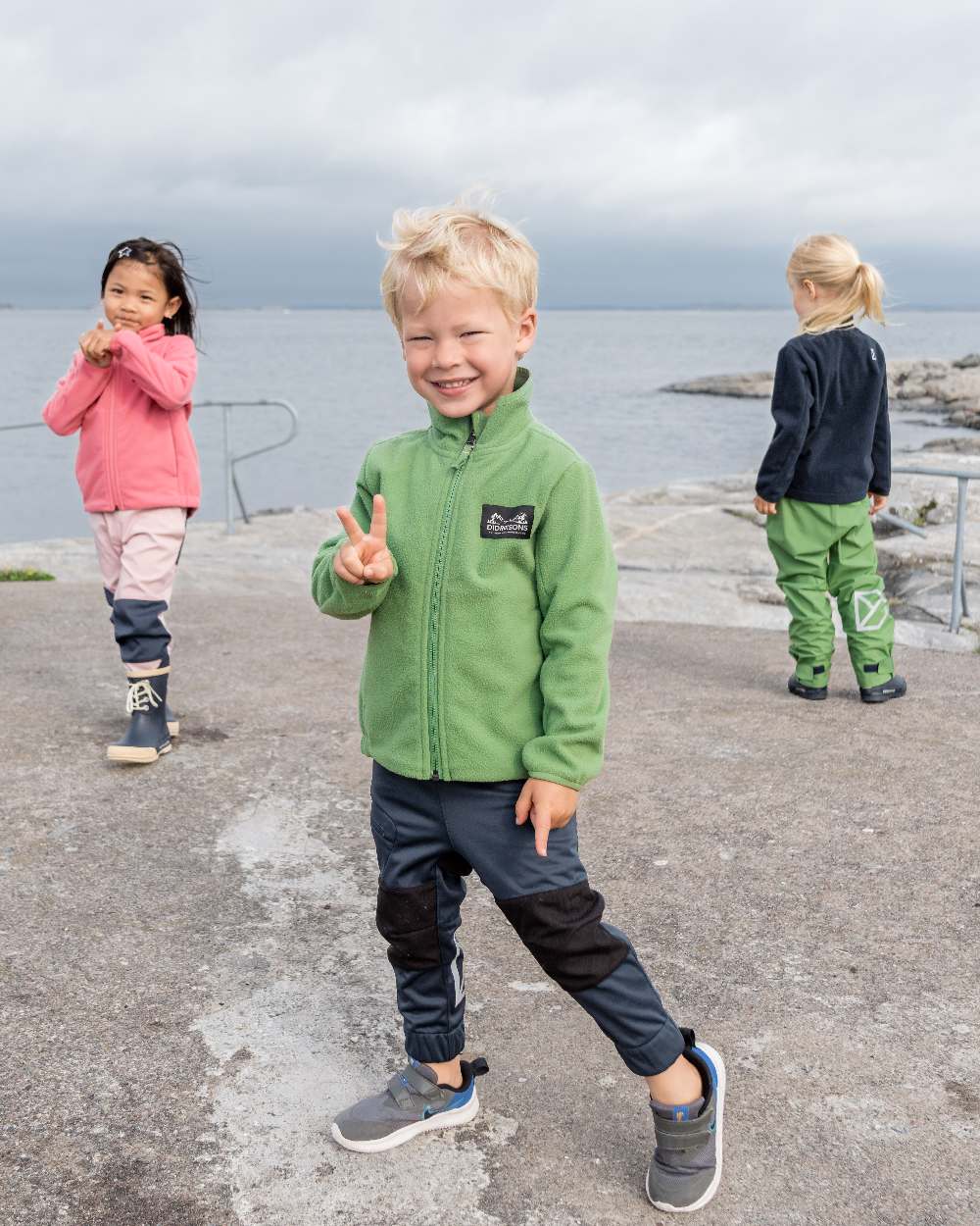 Algae Green coloured Didriksons Childrens Muskot Jacket on coastal background 