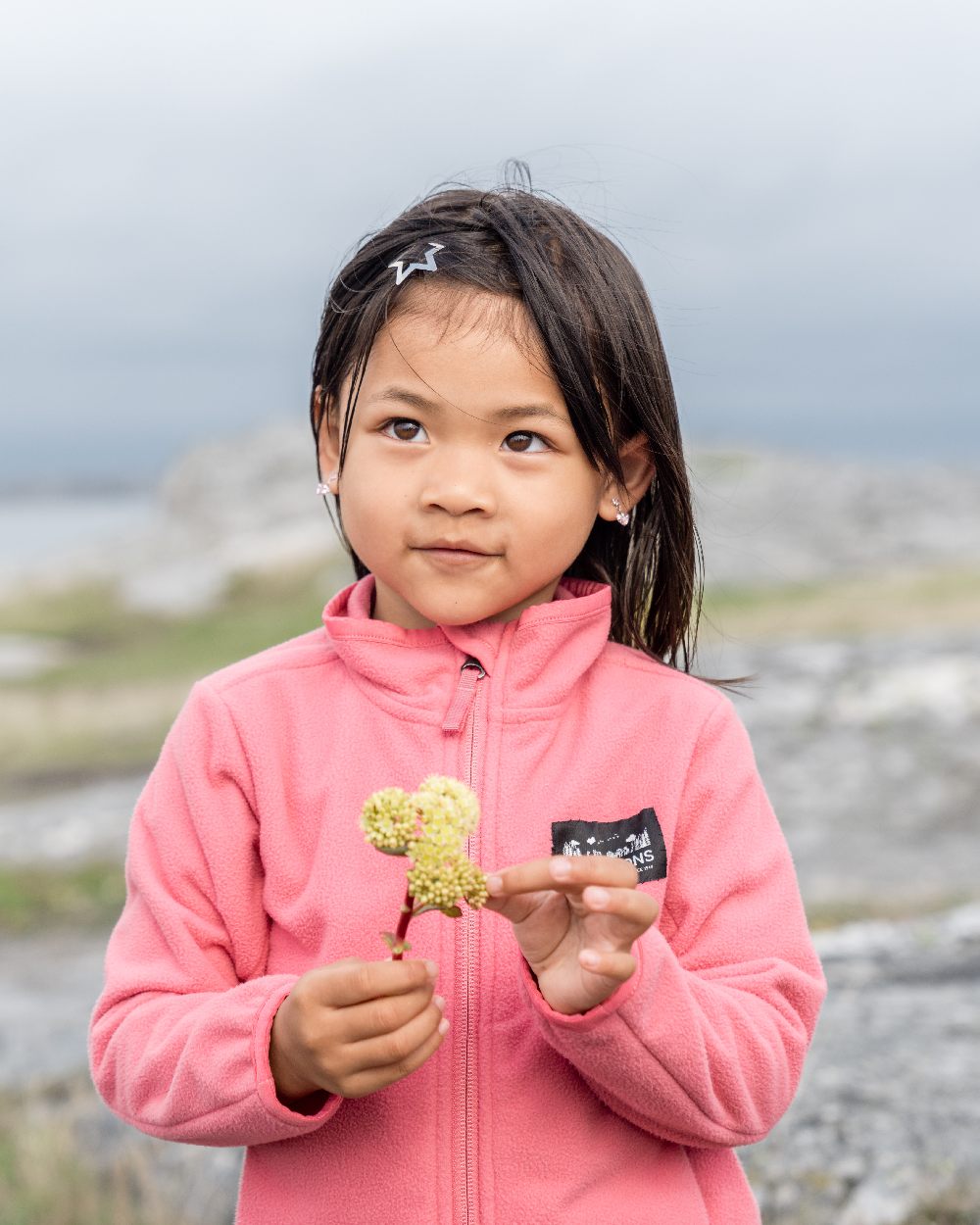 Dusty Azalea coloured Didriksons Childrens Muskot Jacket on blurry background 