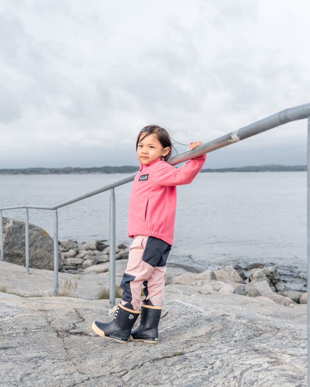 Dusty Azalea coloured Didriksons Childrens Muskot Jacket on coastal background 