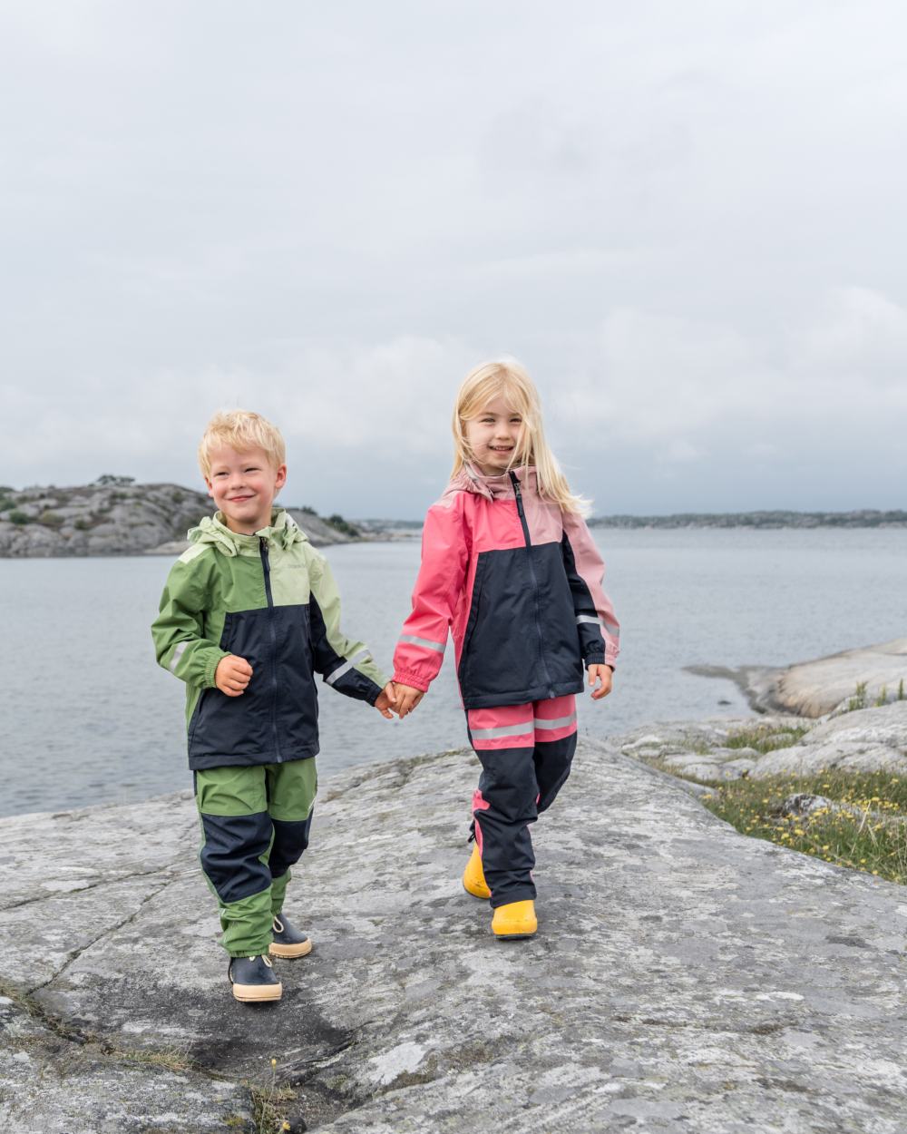 Soft Pink coloured Didriksons Childrens Pilvi Jacket on coastal background 