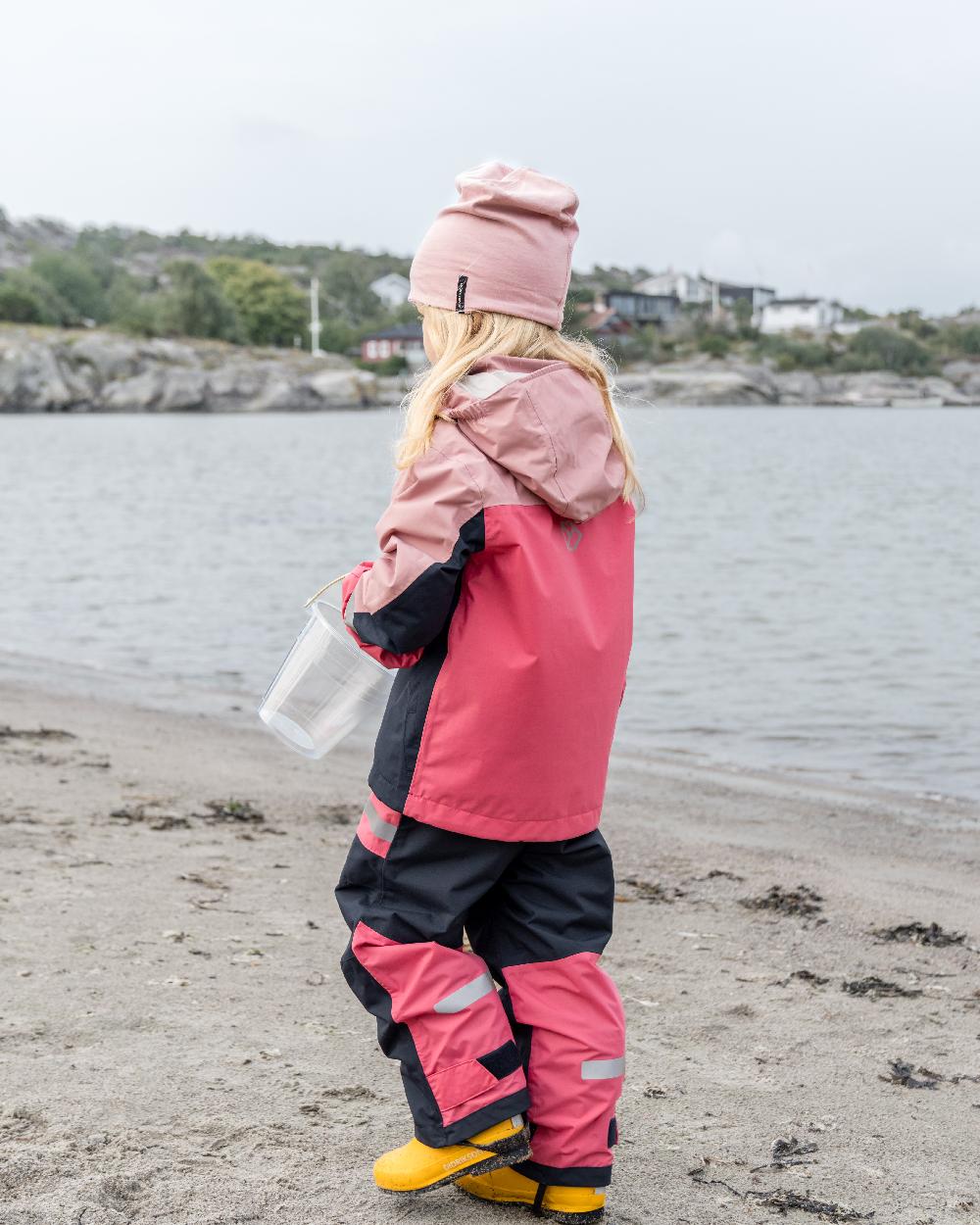 Soft Pink coloured Didriksons Childrens Pilvi Jacket on coastal background 