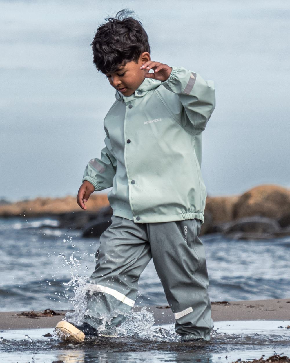 Ocean Mint coloured Didriksons Childrens Slaskeman Rain Set 2 on sea background 