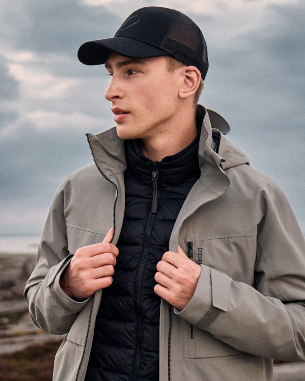 Ash Brown coloured Didriksons Mens Aston Waterproof Jacket on sea background 