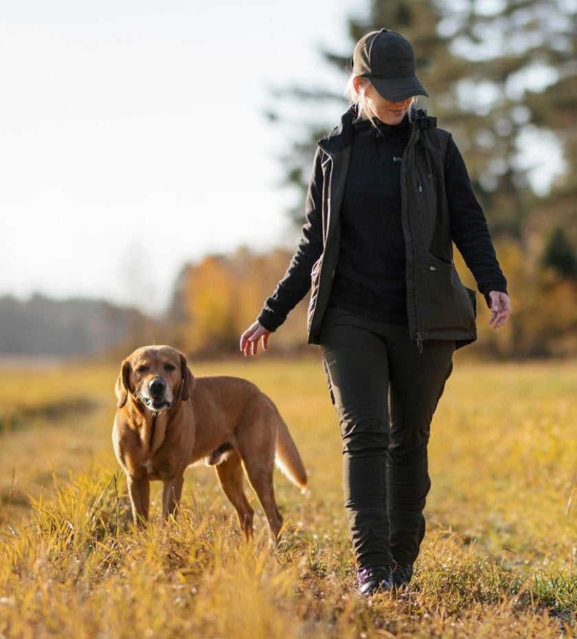Woman walking with a dog in open countryside during outdoor dog training