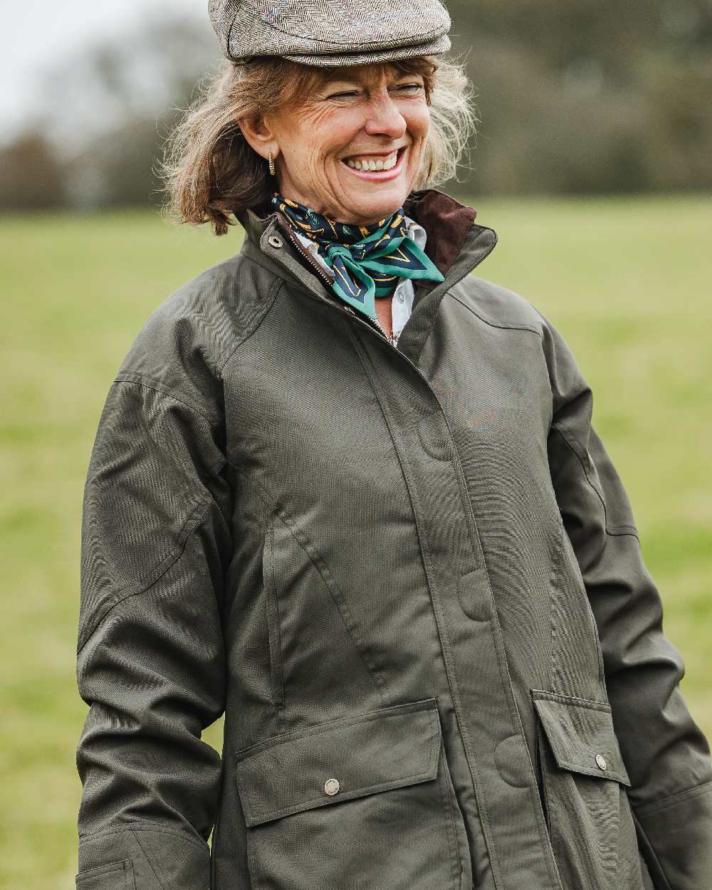 Ivy Coloured Dubarry Castlehyde All-Purpose Shooting Coat on blurry background 