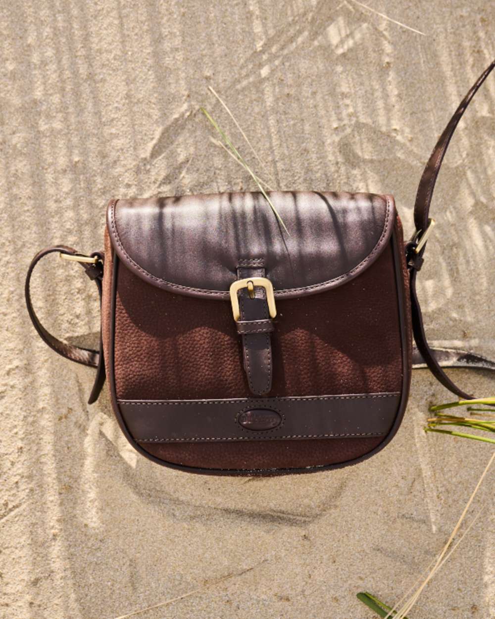 Mocha coloured Dubarry Clara Leather Saddle Bag on sand background 