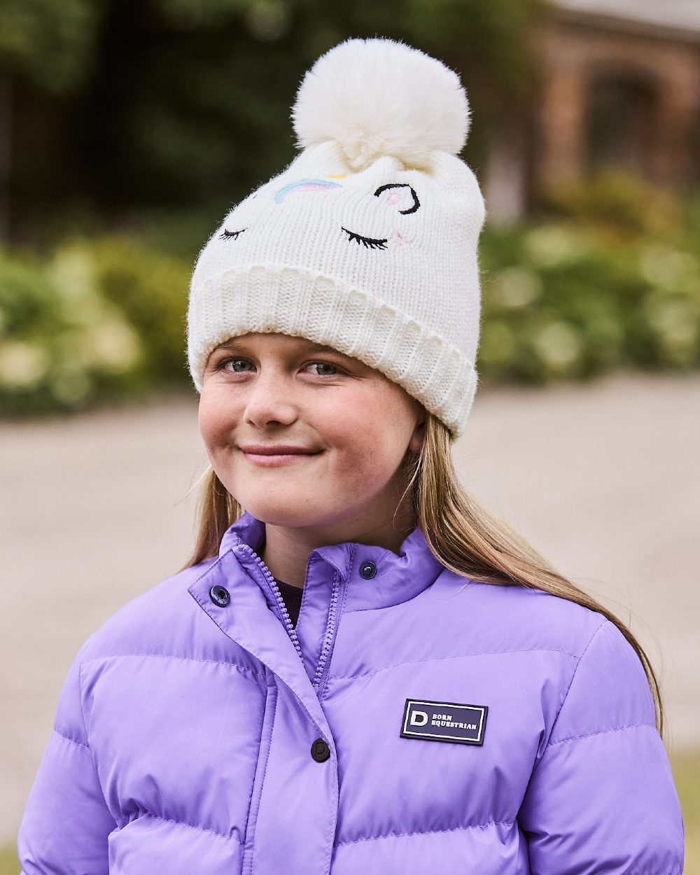 White coloured Dublin Childrens Embroidered Unicorn Beanie on blurry background 