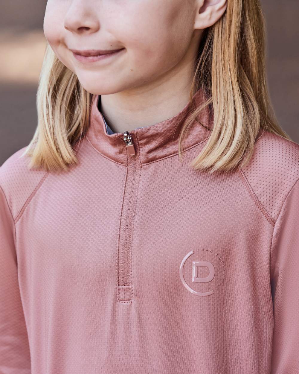 Dusty Rose coloured Dublin Kids Breathable Long Sleeve Riding Top on blurry background 