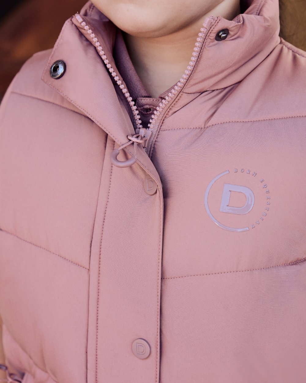 Dusty Rose coloured Dublin Kids Puffer Body Warmer on blurry background 
