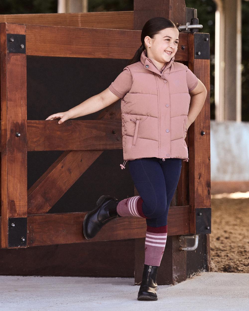 Dusty Rose coloured Dublin Kids Puffer Body Warmer on wood background 