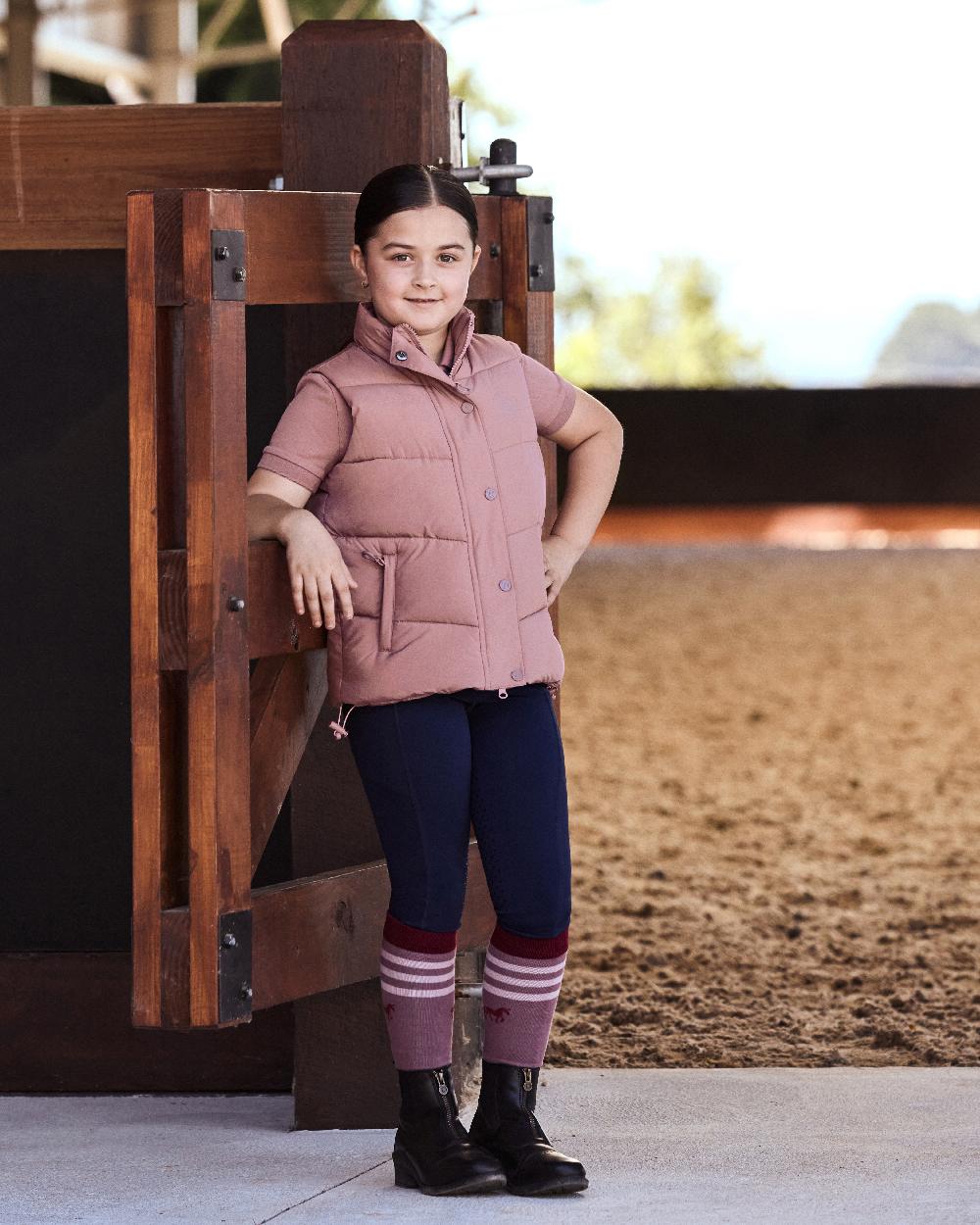 Dusty Rose coloured Dublin Kids Puffer Body Warmer on wood background 