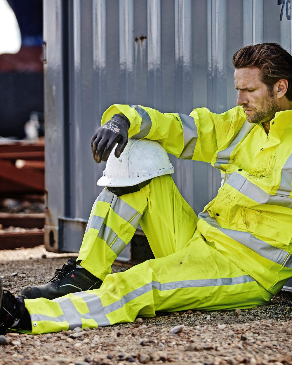 Fluorescent Yellow Coloured Elka Mens Dry Zone Visible Hi-Vis Rain Trousers With Vertical Reflective Stripes on construction background 