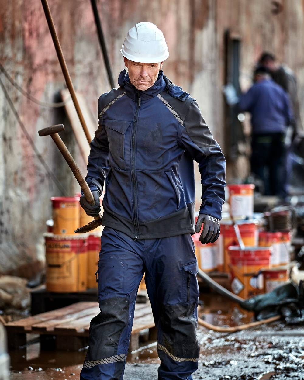 Navy Black Coloured Elka Mens Working Xtreme Softshell Jacket With Detachable Sleeves on construction background 