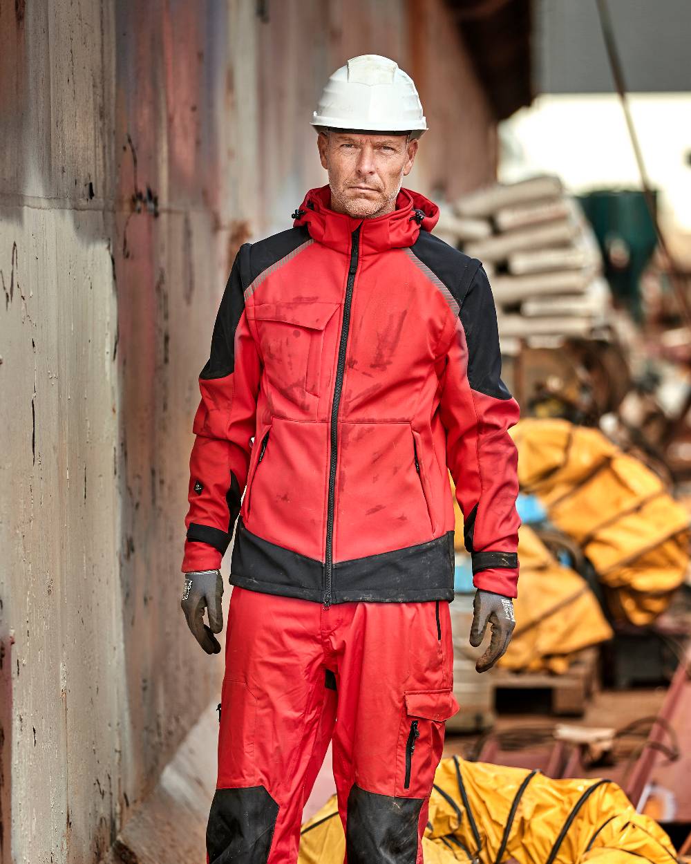Red Black Coloured Elka Mens Working Xtreme Softshell Jacket With Detachable Sleeves on construction background 