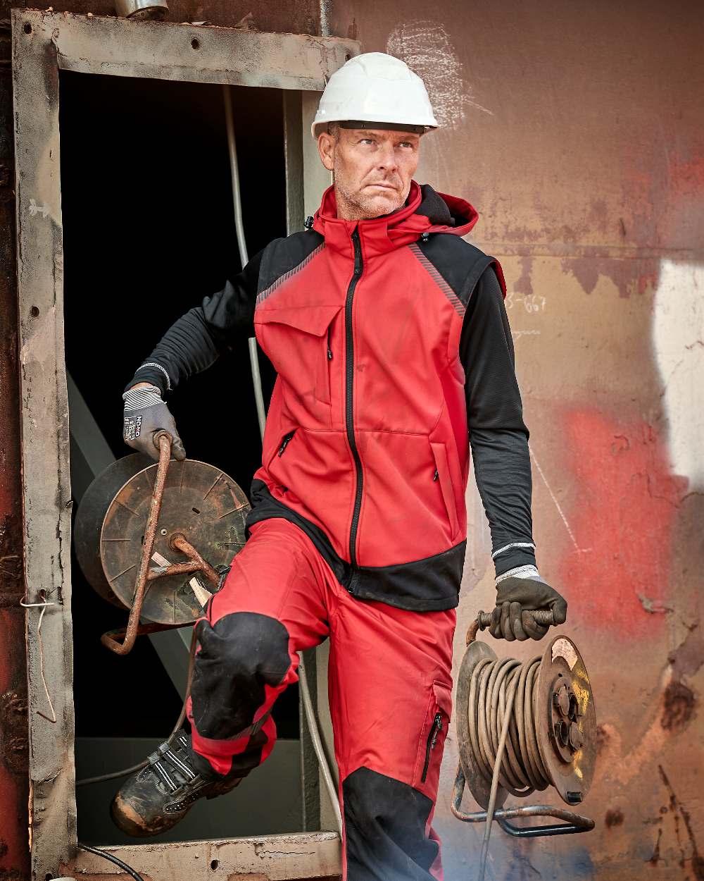 Red Black Coloured Elka Mens Working Xtreme Softshell Jacket With Detachable Sleeves on construction background 