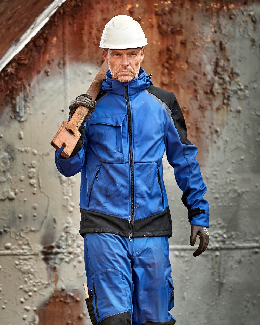 Royal Blue Black Coloured Elka Mens Working Xtreme Softshell Jacket With Detachable Sleeves on construction background 