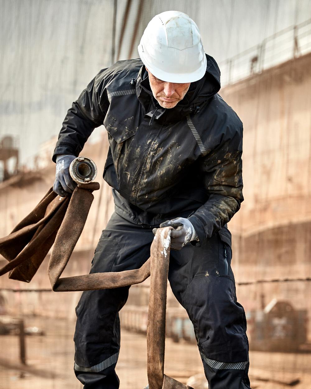 Black Coloured Elka Mens Working Xtreme Stretch Winter Jacket on construction background 