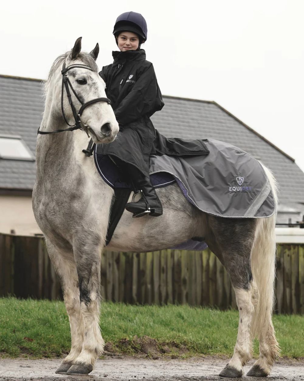 Black coloured Equidry Children Pro Ride Evolution Thin Fleece With Stowaway Hood on farm background 
