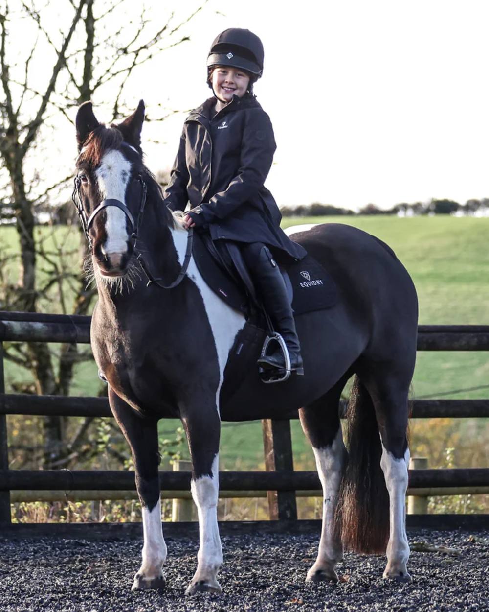 Black coloured Equidry Childrens Bronte Riding Coat on grassy background 