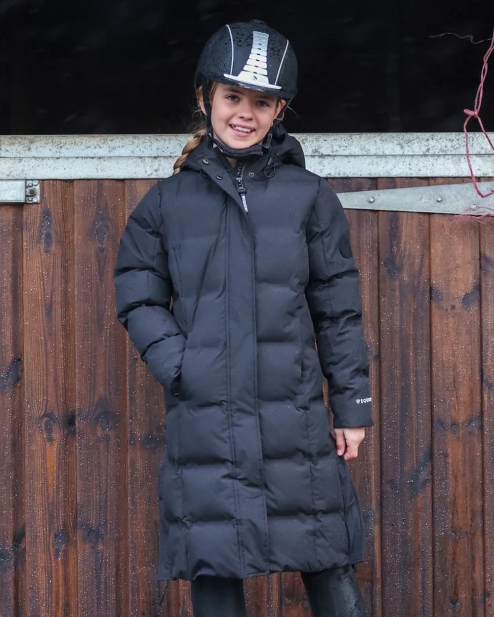 Black coloured Equidry Childrens Thora Waterproof Riding Puffer Jacket With Hood on stable background 