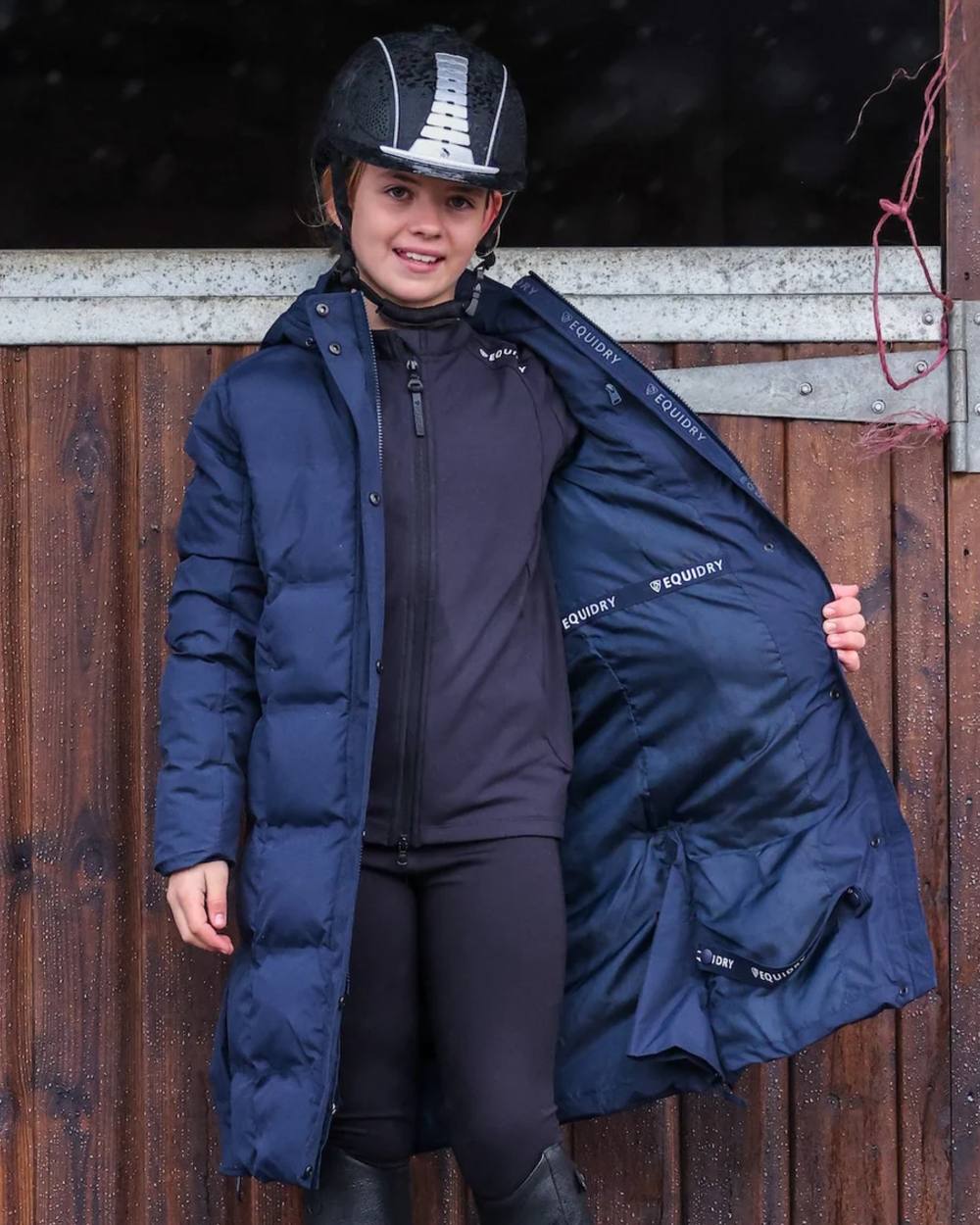 Navy coloured Equidry Childrens Thora Waterproof Riding Puffer Jacket With Hood on stable background 