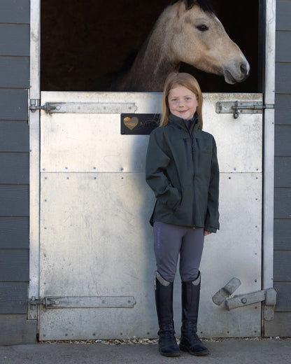 Khaki Equidry Childrens Varsha Waterproof Jacket on yard background 