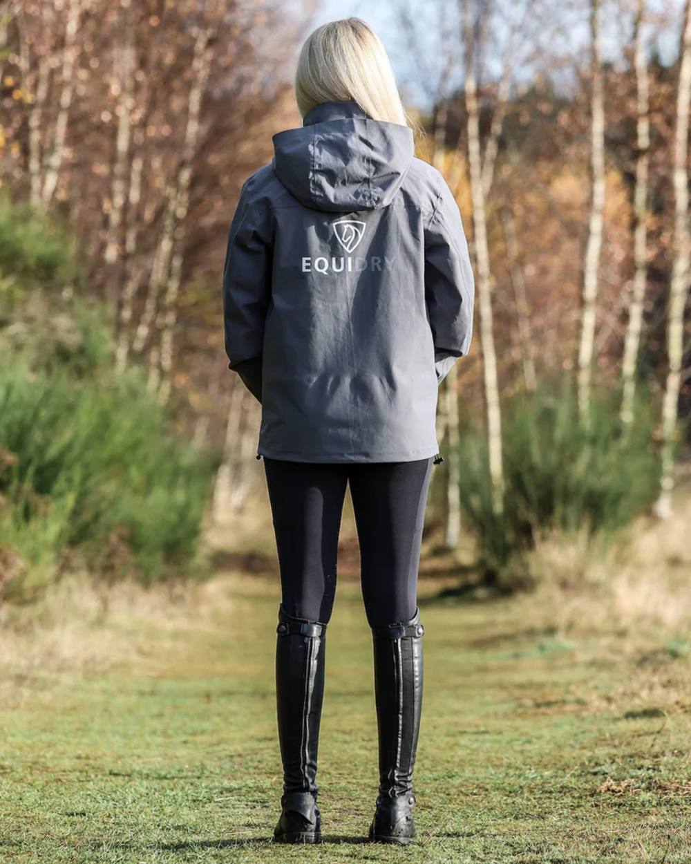 Charcoal coloured Equidry Womens Nimbus Pack Away Jacket with Stowaway Hood on forest background 
