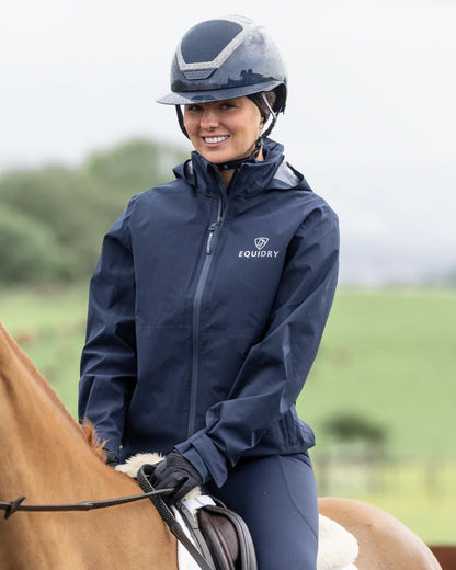Navy coloured Equidry Womens Nimbus Pack Away Jacket with Stowaway Hood on blurry background 