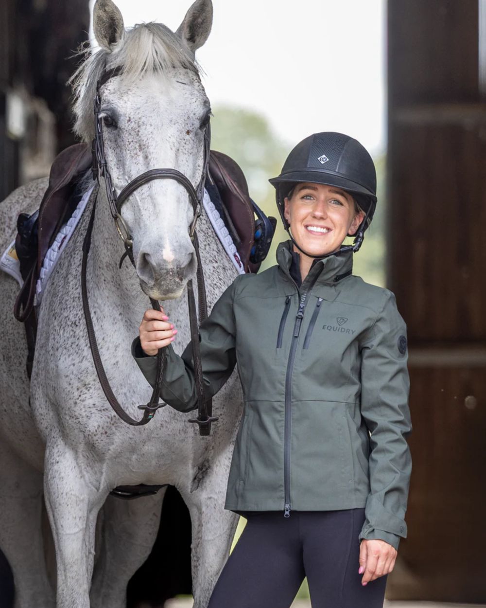 Khaki coloured Equidry Womens Varsha Jacket with Stowaway Hood on stable background 