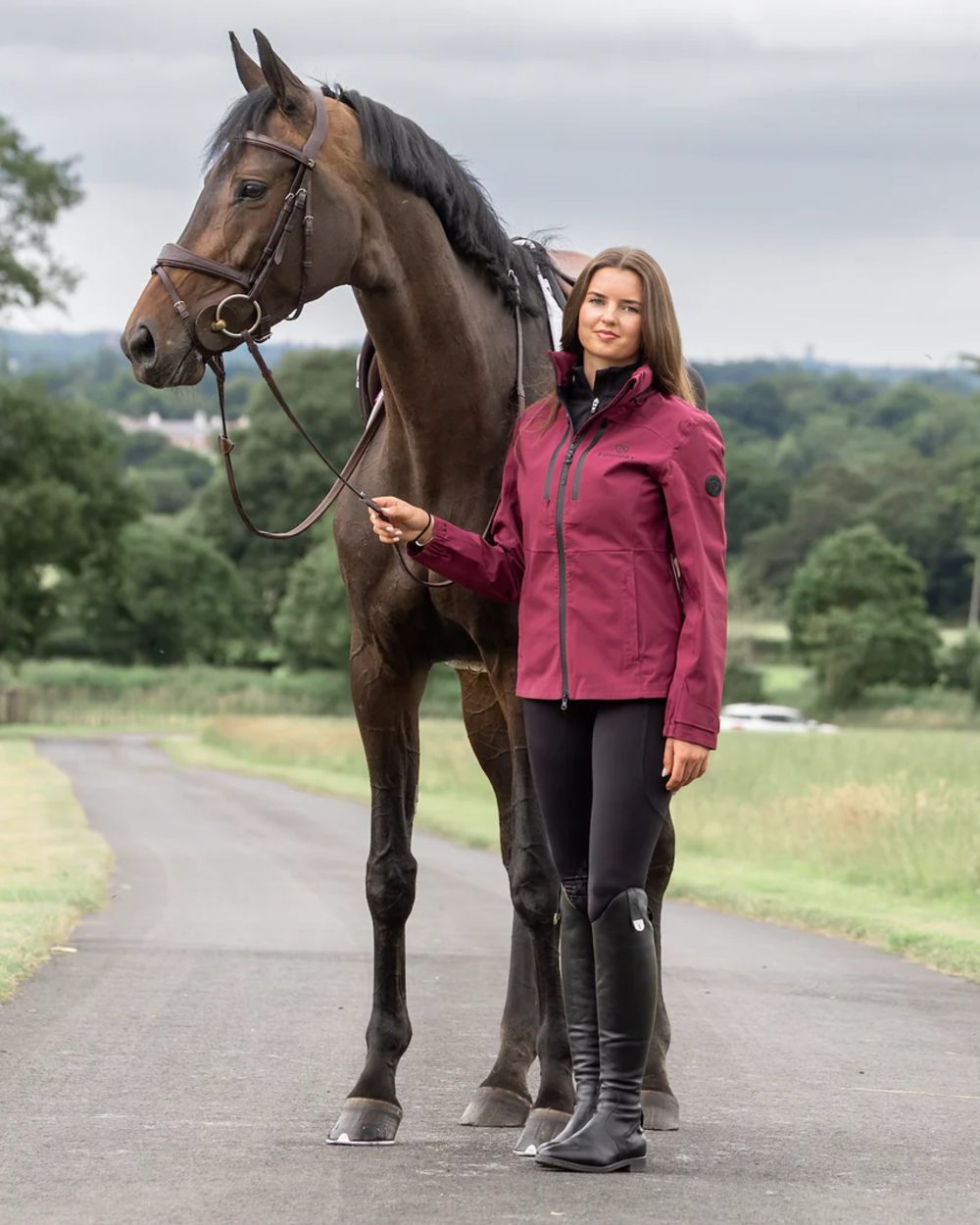 Plum coloured Equidry Womens Varsha Jacket with Stowaway Hood on street background 